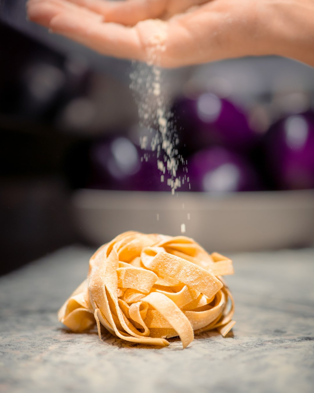 Farine versée à la main sur des pâtes fraîches dans la cuisine de la Trattoria Bella